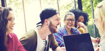 People around table having discussion and taking notes on a laptop