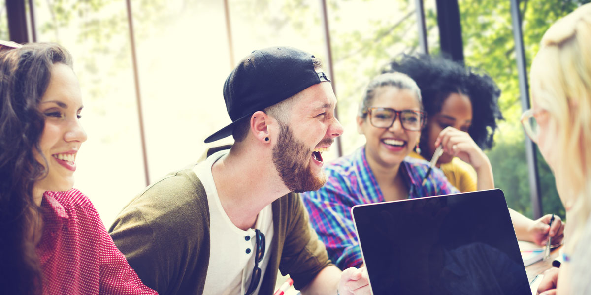 People around table having discussion and taking notes on a laptop