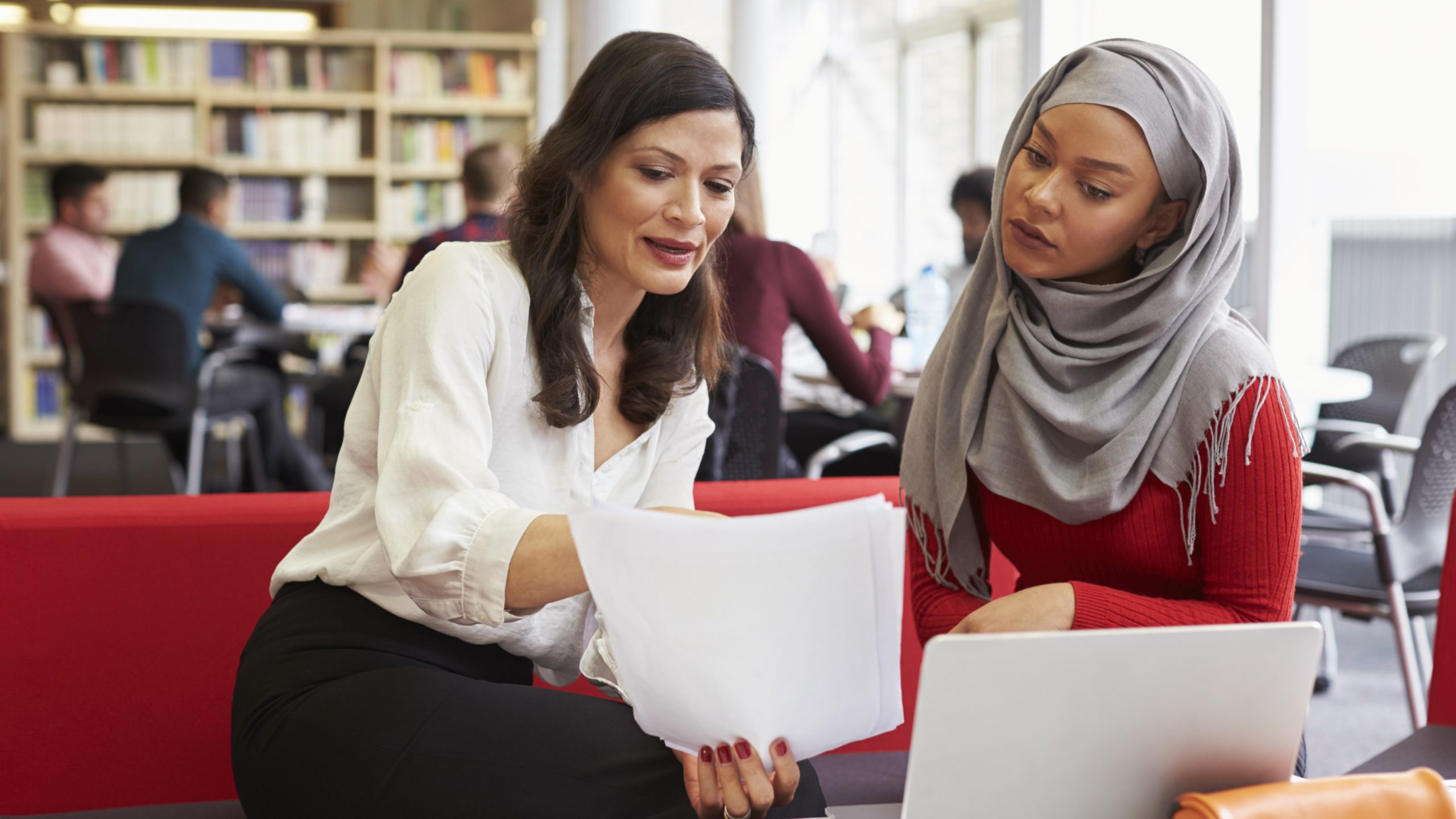 Female University Student Working In Library With Tutor